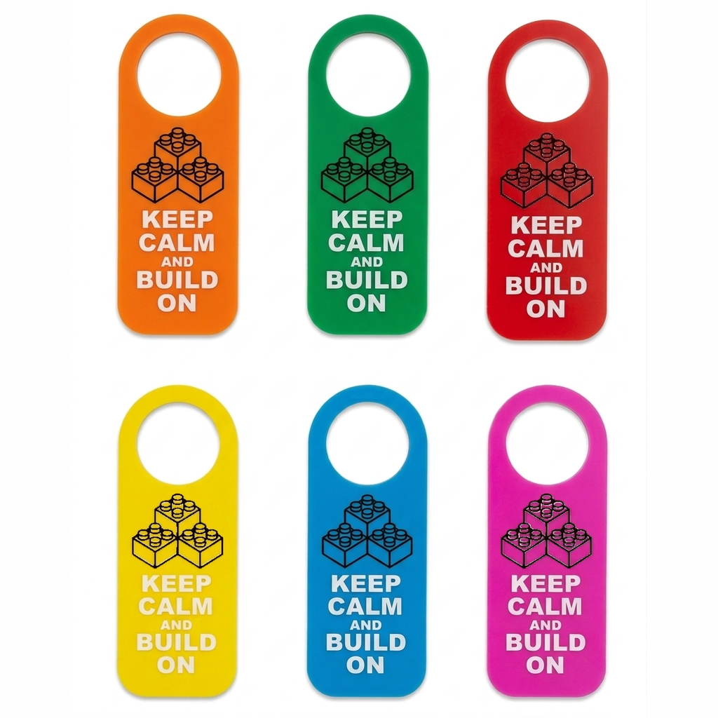 Six hanging door hangers in orange, green, red, yellow, blue, and pink, each printed with a black LEGO-style brick graphic and the text 'KEEP CALM AND BUILD ON'.