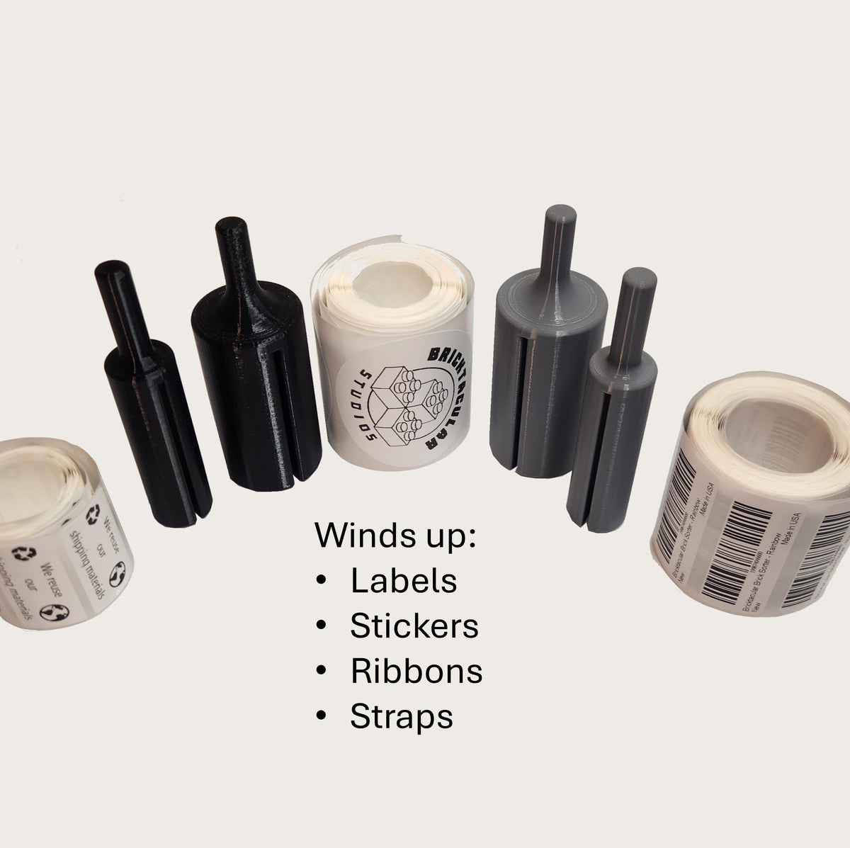 A set of label winder drill attachments next to several rolls of labels that were wound up using the label winder.
